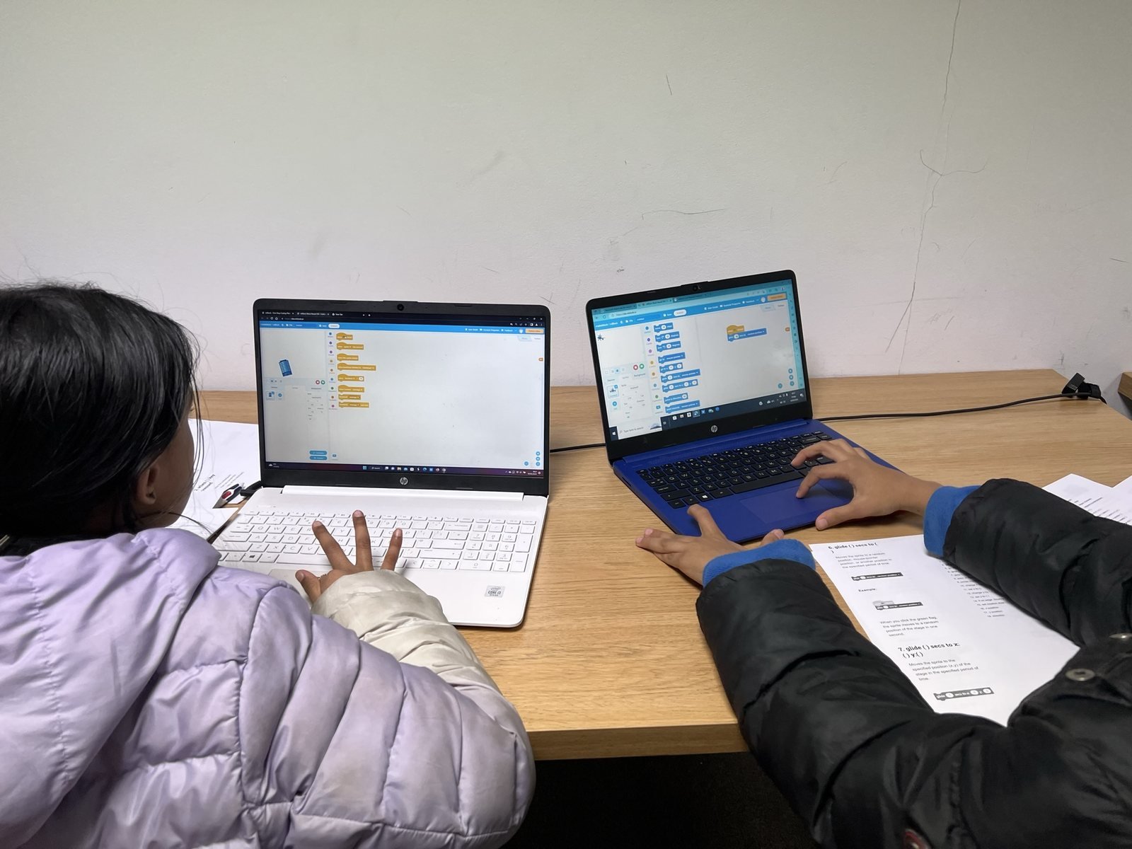 Children working on coding tasks using laptops